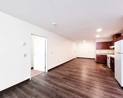 A kitchen with white appliances and brown wood flooring.