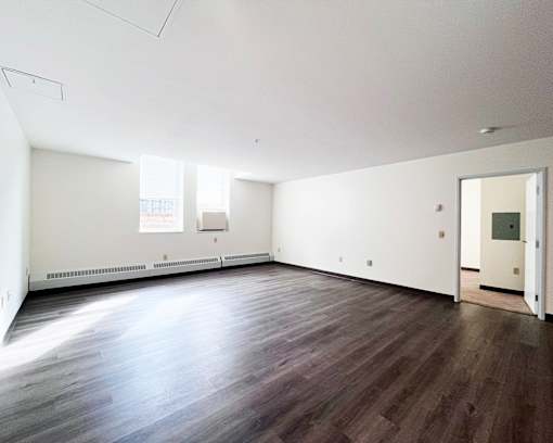 A large empty room with wooden floors and white walls.