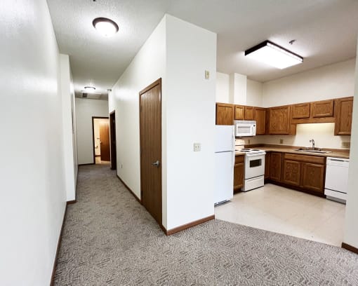 an empty kitchen with white appliances and wooden cabinets