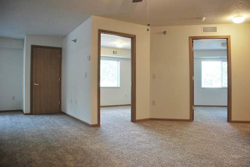 A room with a carpeted floor and three doors.