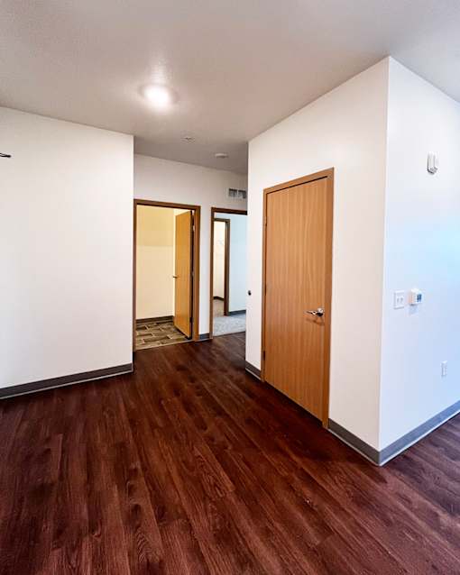 A hallway with wood floors and white walls.