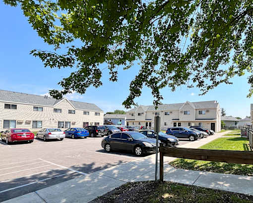 A parking lot with cars and apartment buildings in the background.