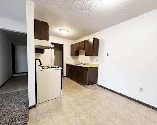 an empty kitchen with white appliances and brown cabinets