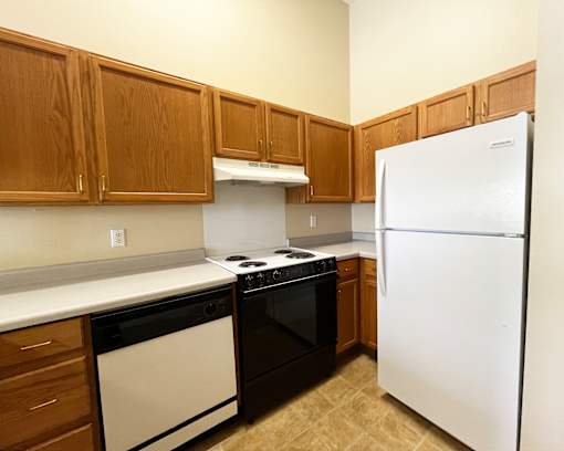 A kitchen with brown cabinets and a white refrigerator.