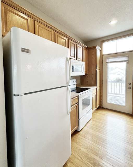A white refrigerator in a kitchen with wooden cabinets.