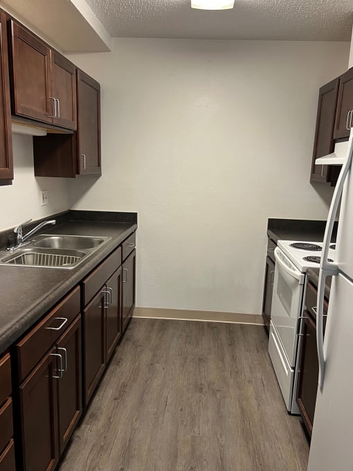 a kitchen with dark cabinets and white appliances