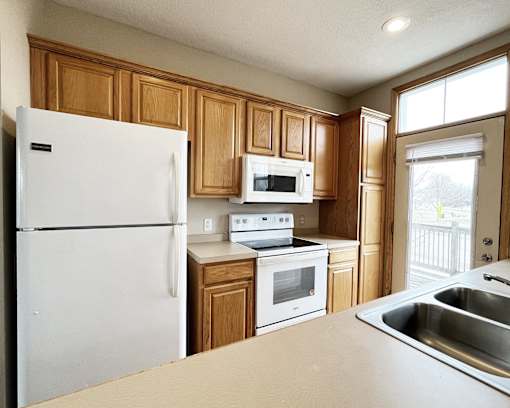 A kitchen with wooden cabinets and white appliances.