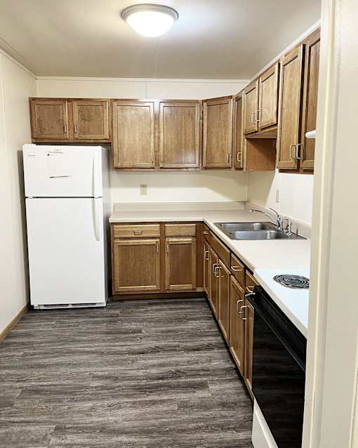 an empty kitchen with wooden cabinets and a white refrigerator