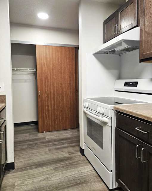 A kitchen with a white oven and wooden cabinets.