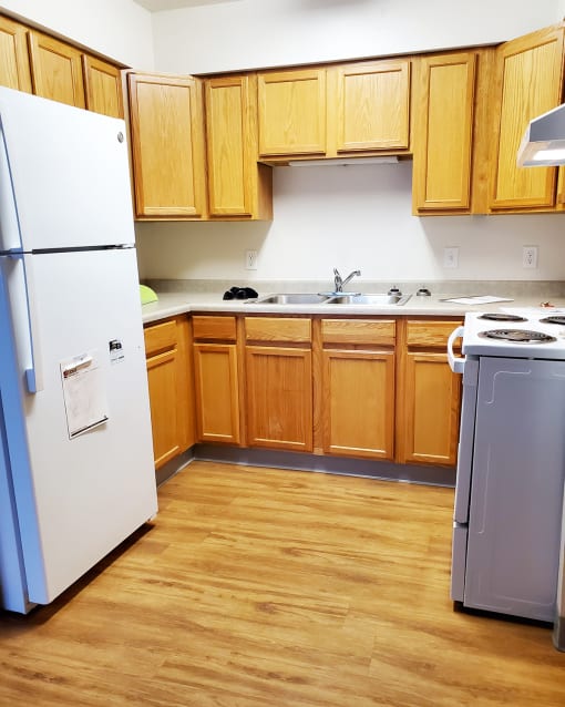 a kitchen with wooden cabinets and a refrigerator and a sink