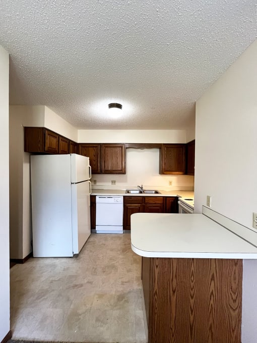 an empty kitchen with white appliances and wooden cabinets
