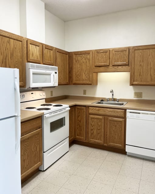 an empty kitchen with white appliances and wooden cabinets