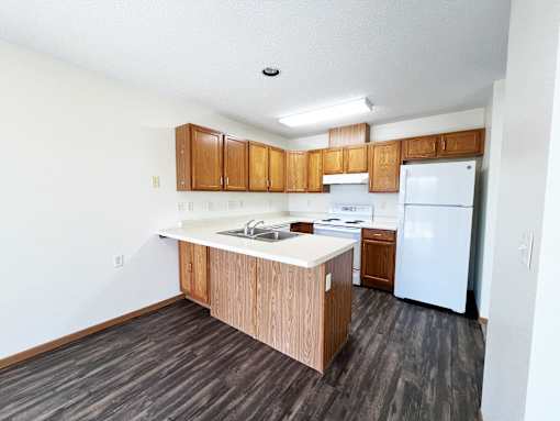 an empty kitchen with white appliances and wooden cabinets