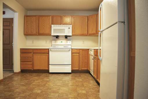 A kitchen with brown cabinets and white appliances.
