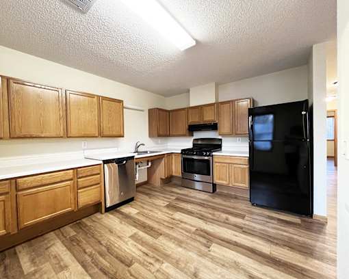 A kitchen with wooden cabinets and a black refrigerator.