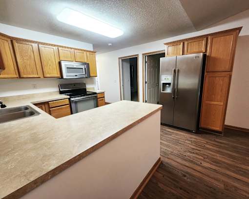 A kitchen with wooden cabinets and a stainless steel refrigerator.