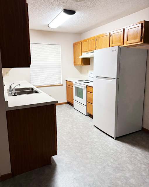 A kitchen with a white refrigerator, sink, and stove.