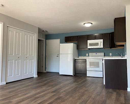 A kitchen with a white refrigerator and wooden floors.