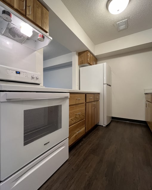 redesigned kitchen with white appliances and wood flooring in an apartment