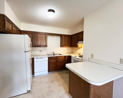 an empty kitchen with white appliances and wooden cabinets