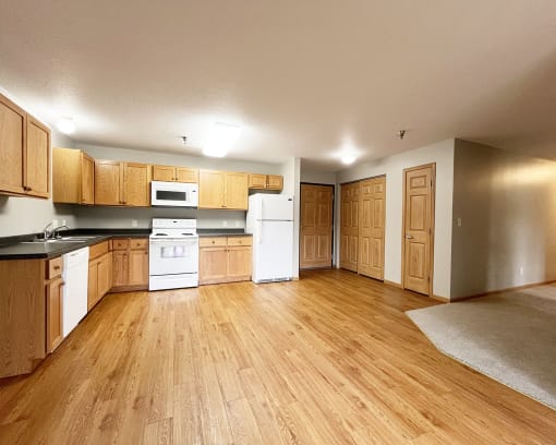 an empty kitchen with wooden floors and white appliances