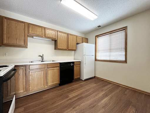 an empty kitchen with wooden cabinets and a refrigerator