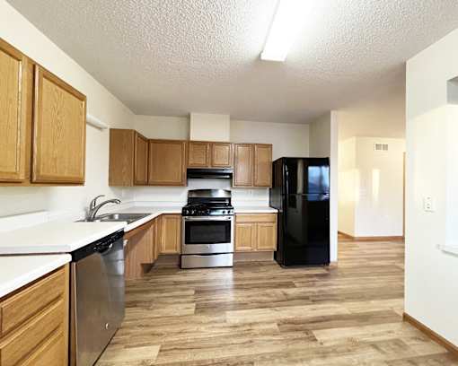 A kitchen with wooden cabinets and a black refrigerator.