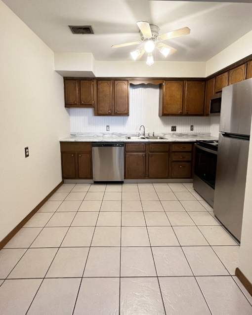 A kitchen with white tile floors and wooden cabinets.