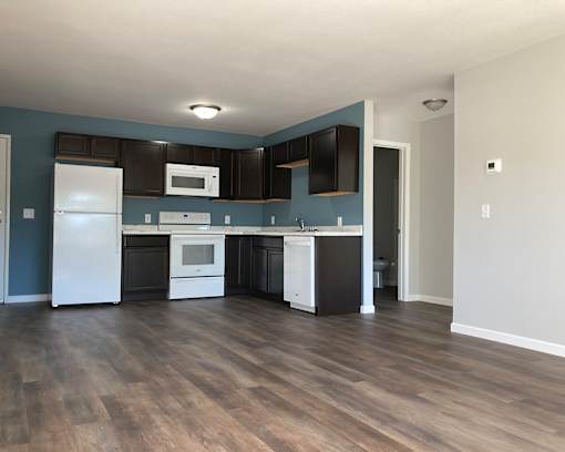 A kitchen with a white refrigerator, black cabinets, and a white oven.