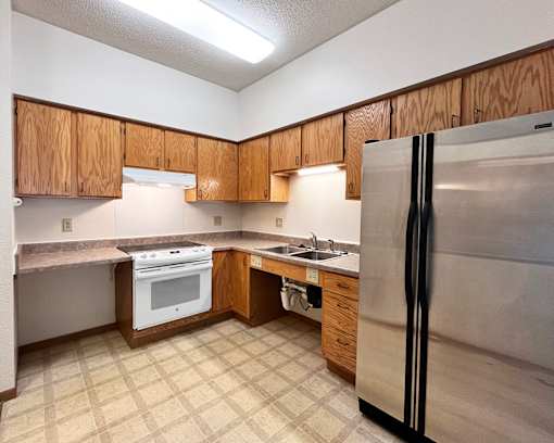 A kitchen with a refrigerator, oven, and sink.