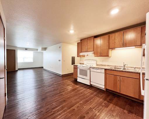 A kitchen with wooden floors and white appliances.