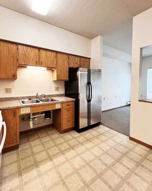 A kitchen with a sink, dishwasher, and refrigerator.