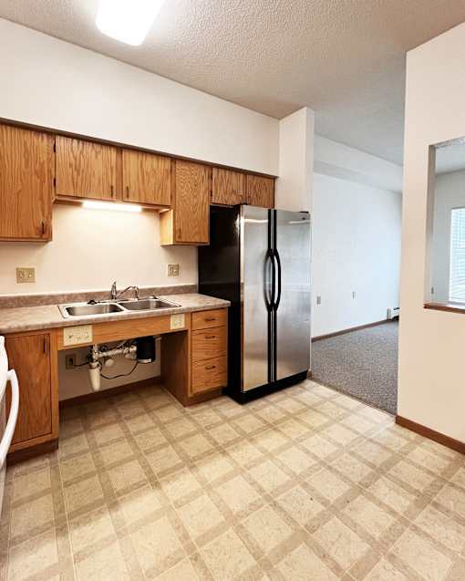 A kitchen with a sink, dishwasher, and refrigerator.