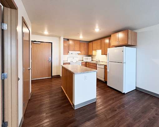 A kitchen with white appliances and wooden cabinets.