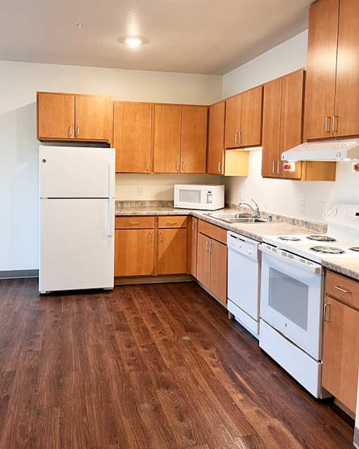 A kitchen with white appliances and wooden cabinets.