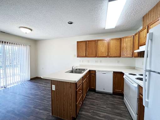 an empty kitchen with white appliances and wooden cabinets
