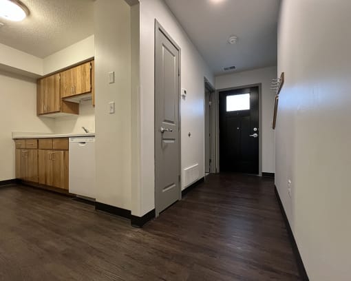 an empty kitchen and hallway with white walls and wood flooring