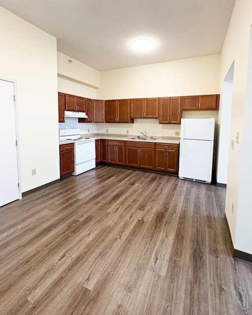 A kitchen with white appliances and wooden floors.