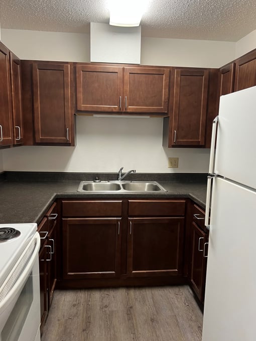 a kitchen with dark wood cabinets and white appliances