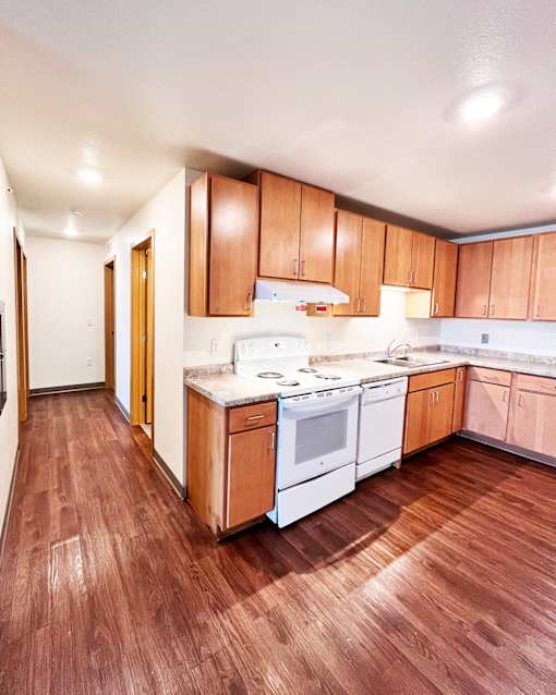 A kitchen with wooden floors and white appliances.