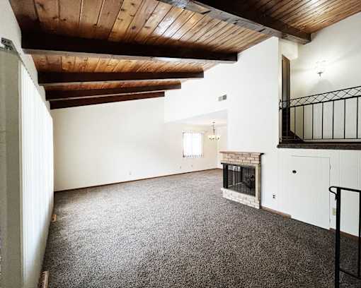 A large, empty room with a fireplace and a balcony.