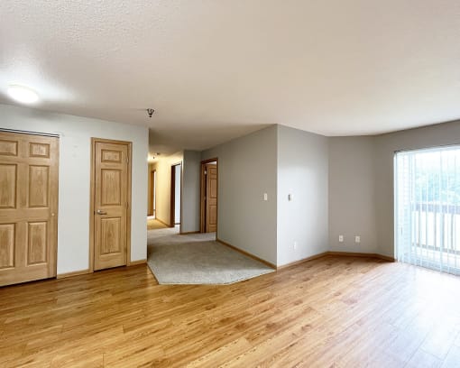 an empty living room with wooden floors and a door