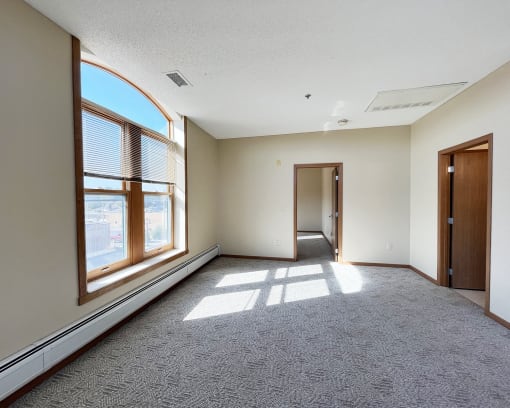an empty room with a large window and a door to a hallway