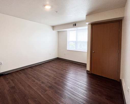 A room with a brown wooden floor and a brown door.