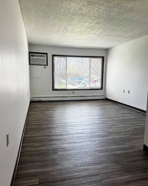 A room with a window and a wooden floor.