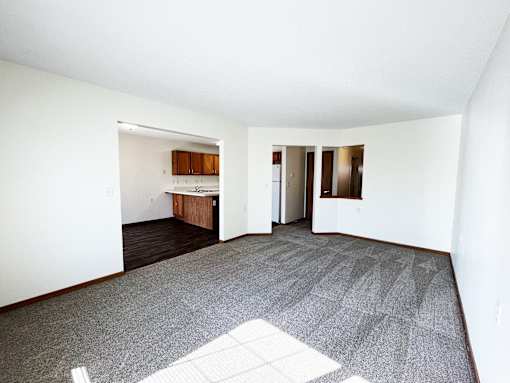 an empty living room and kitchen with white walls and carpet