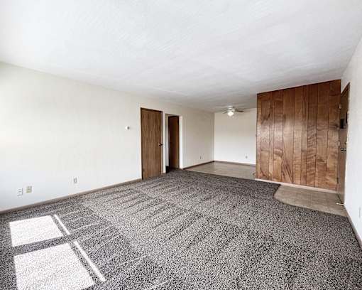 an empty living room with carpet and white walls