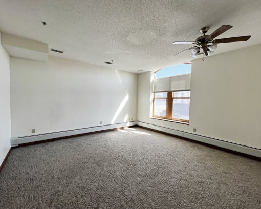 an empty living room with a ceiling fan and a window