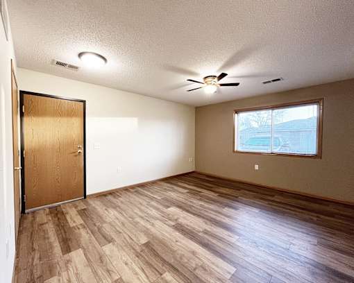 A room with a ceiling fan and a door.