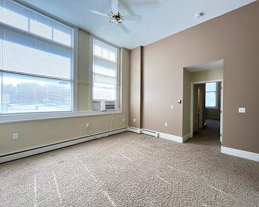 A room with a carpet floor and a ceiling fan.